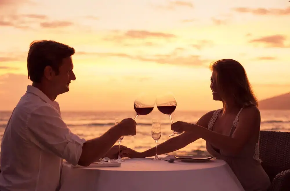 Couple sharing romantic sunset dinner on the beach during a luxurious hawaiian escape