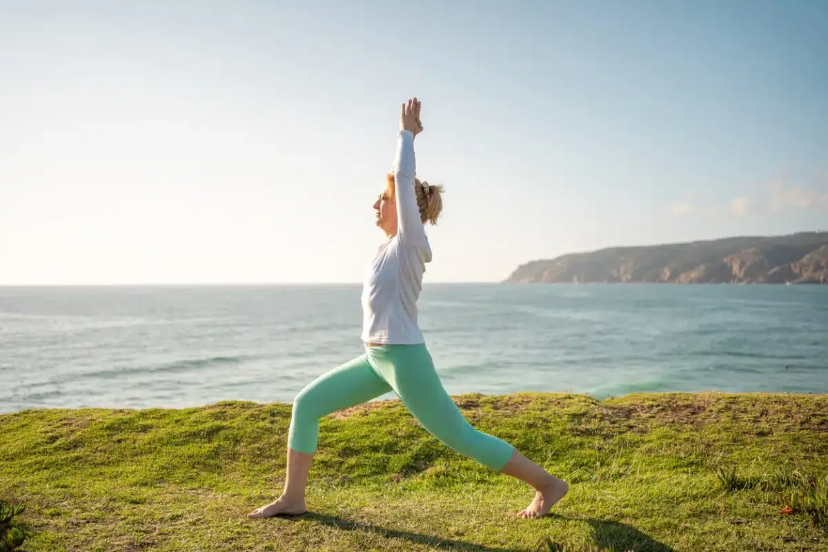 Woman gracefully performs warrior pose, virabhadrasana, on beautiful beach. Practices yoga sunny morning, healthy lifestyle on nature. This serves as wonderful example fitness and wellness.