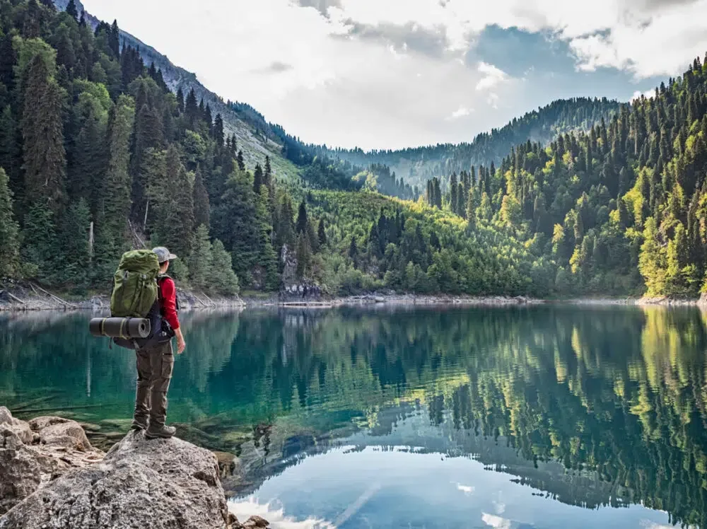 man on the edge of a lake surrounded by mountains