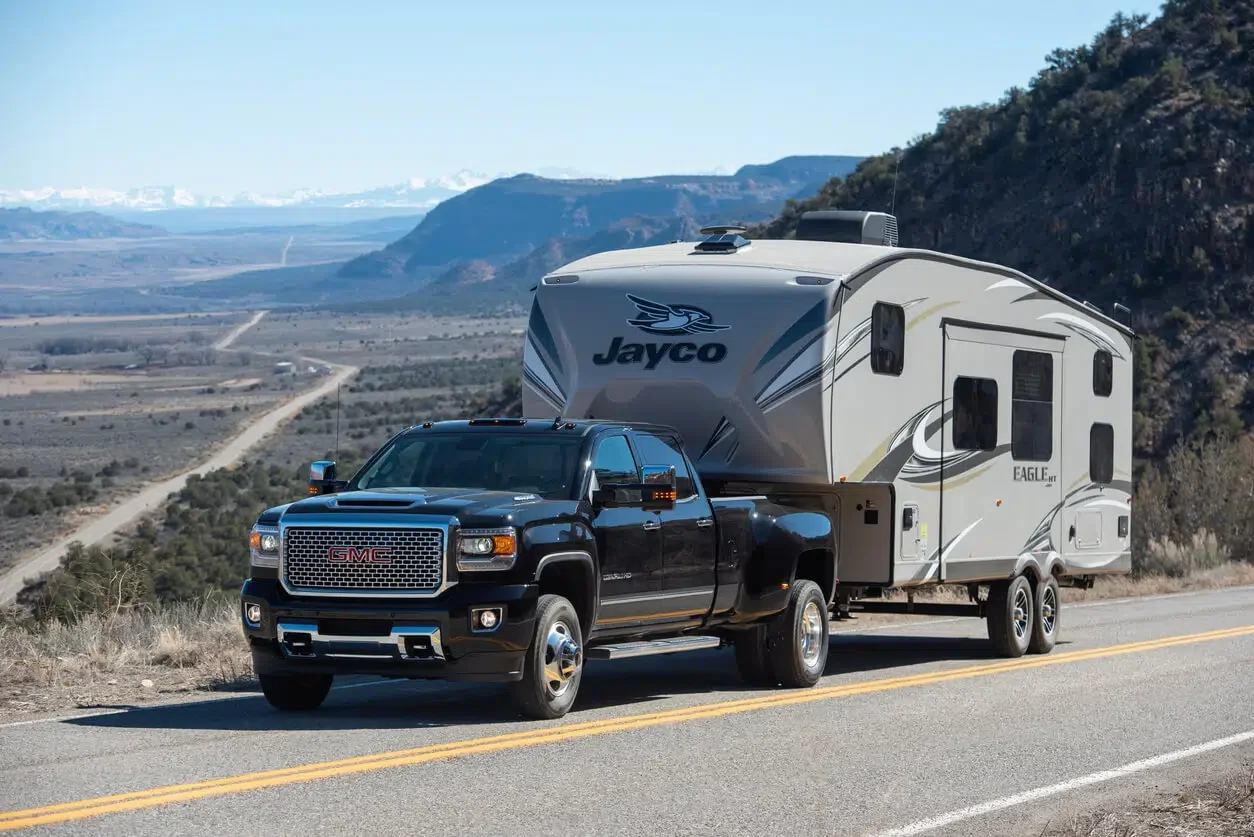 An RVer tows their 5th wheel travel trailer behind a pickup over a country road in northern Arizona mountains.