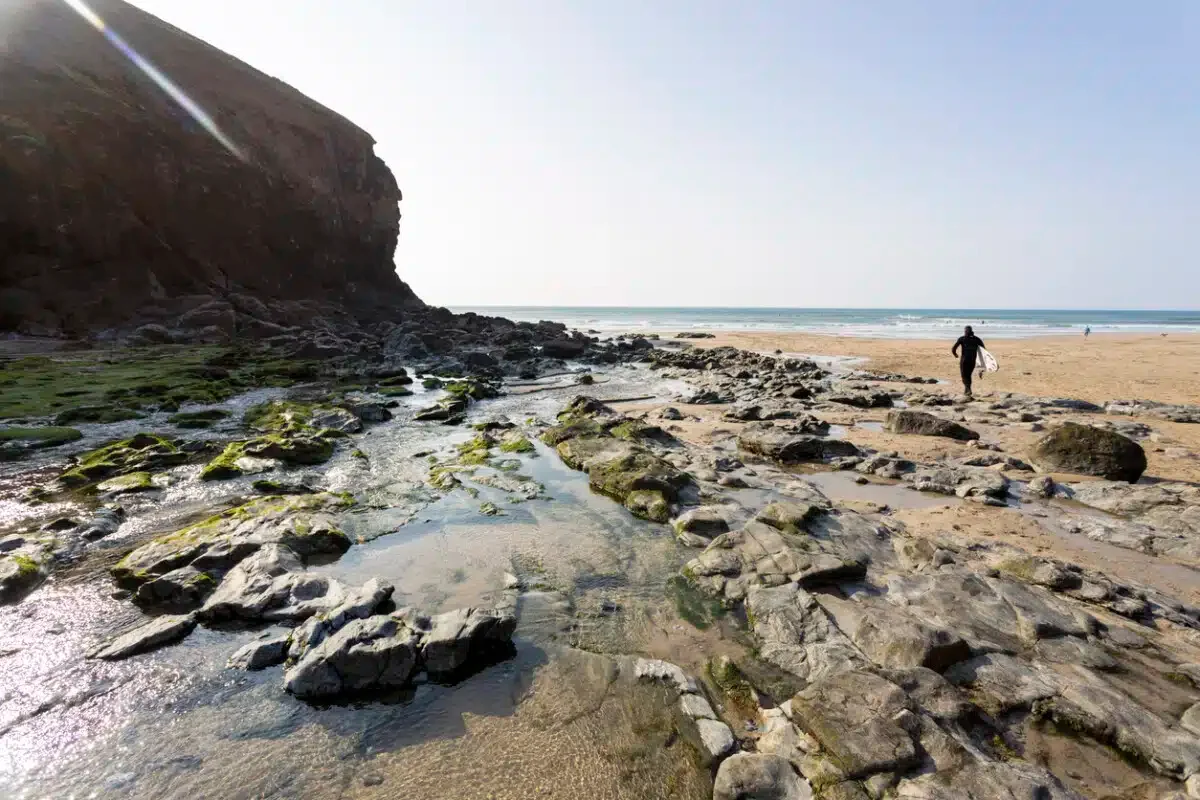A surfer holding his board on the beach