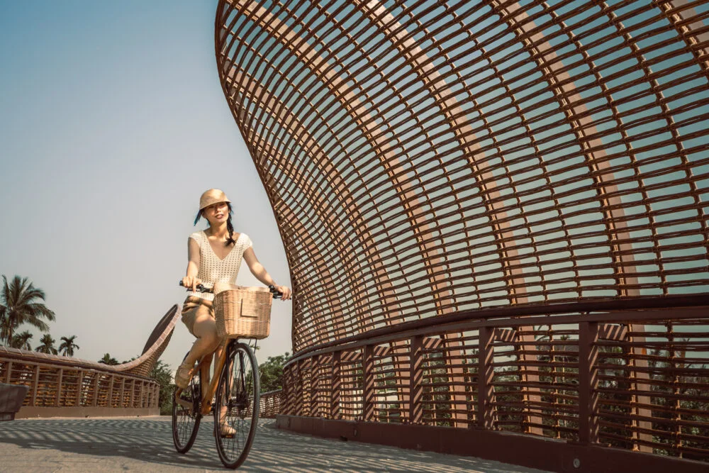 A guest cycling across the resort's distinctive bridge on one of the eco centric bamboo bicycle