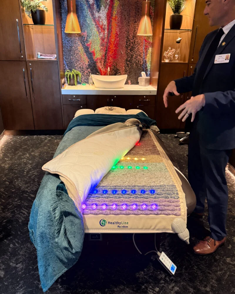 Man showing off a luxury massage table in a spa room
